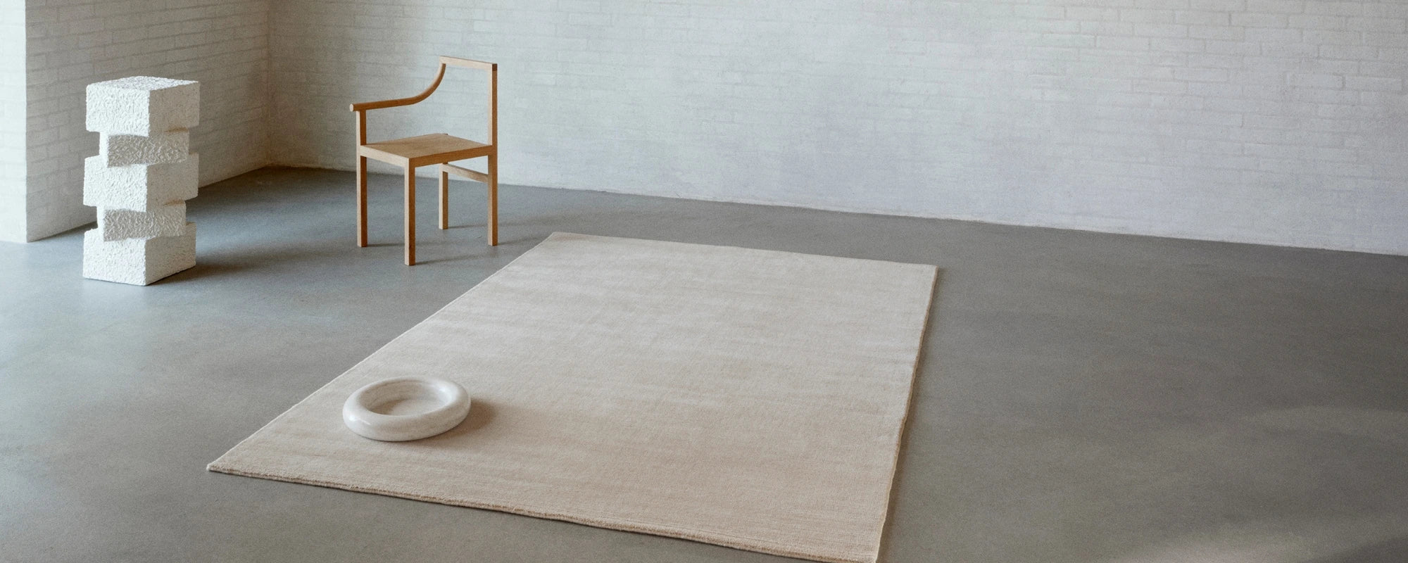 Minimalist room with a rug, chair, and small table.